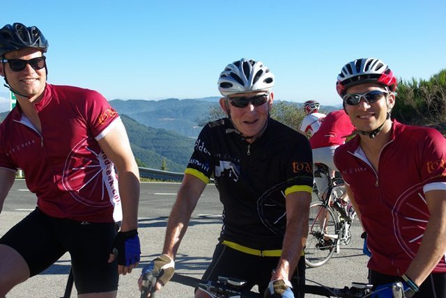 Three cyclists pose in front of an expansive valley view.
