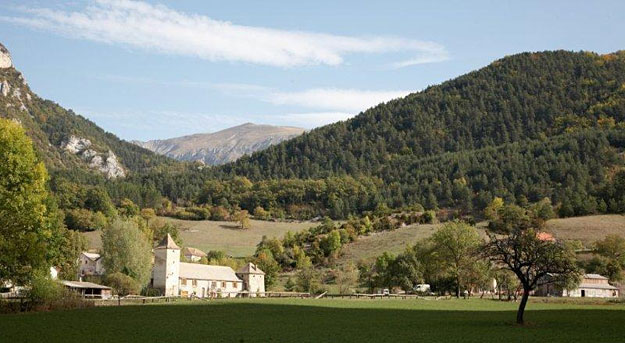 A white church sits in a green valley, with tall green hills behind.