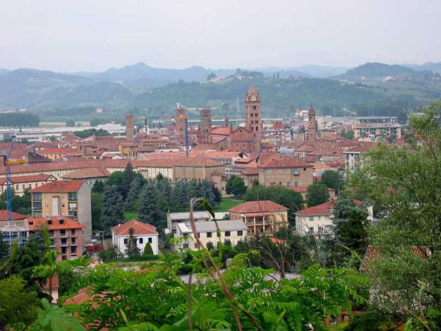 An old town with hills in the background. Some greenery in the foreground.