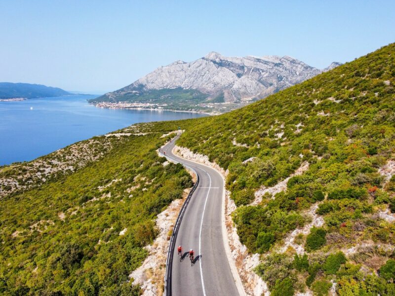 An overhead photo of cyclist on a Ride and Seek biking tour cycling along an isolated stretch of coastal road.