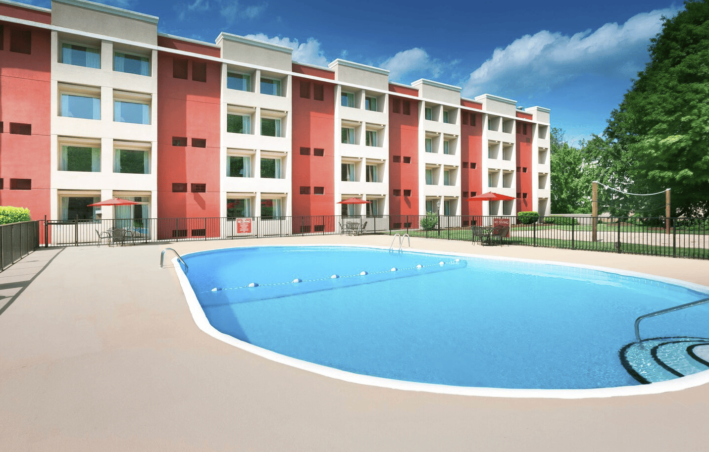 Multistory hotel rooms overlook an oval-shaped pool and pool surrounds.