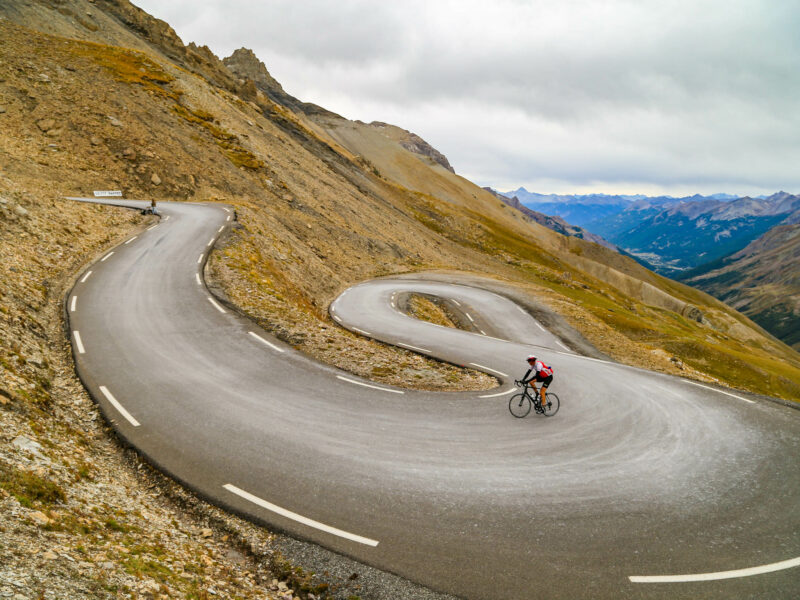 Cyclist riding up through a series of switch-backs towards the top of Col de Galibier in the Italian Alps