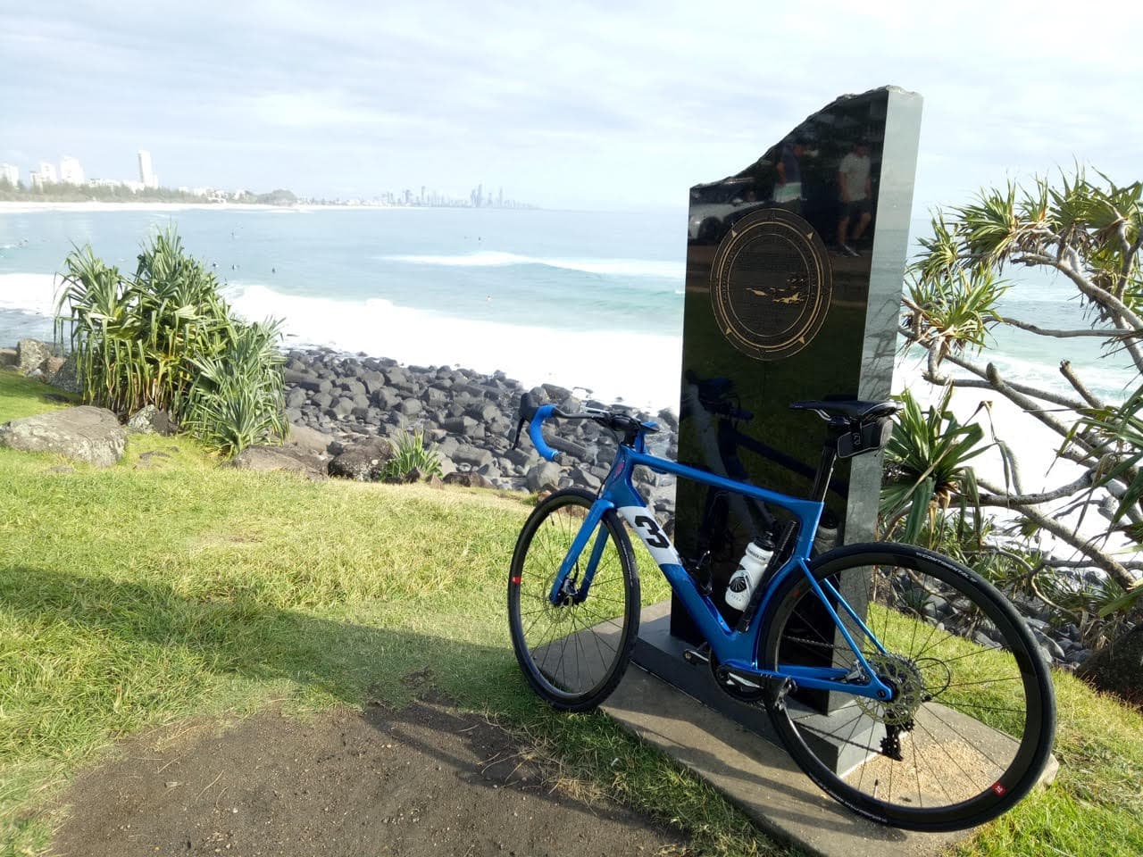 Michael's bike rests against a stone monument overlooking the bay, looking towards the city in the far distance.