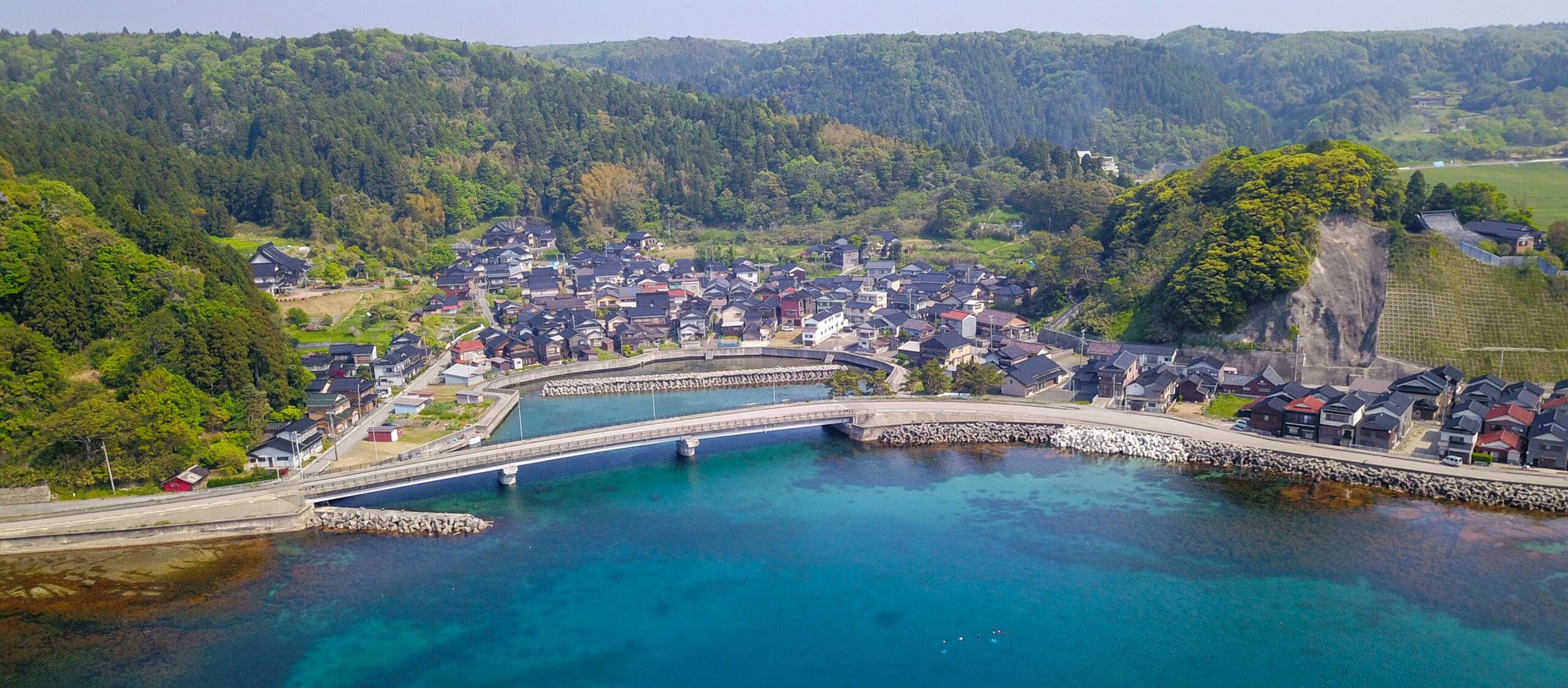 A bridge across the opening of a coastal inlet surrounded by a small town.