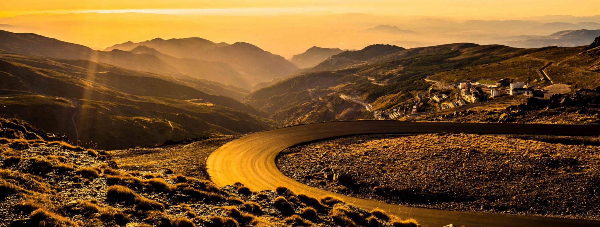 A sweeping bend of a road in the high country in a golden light.