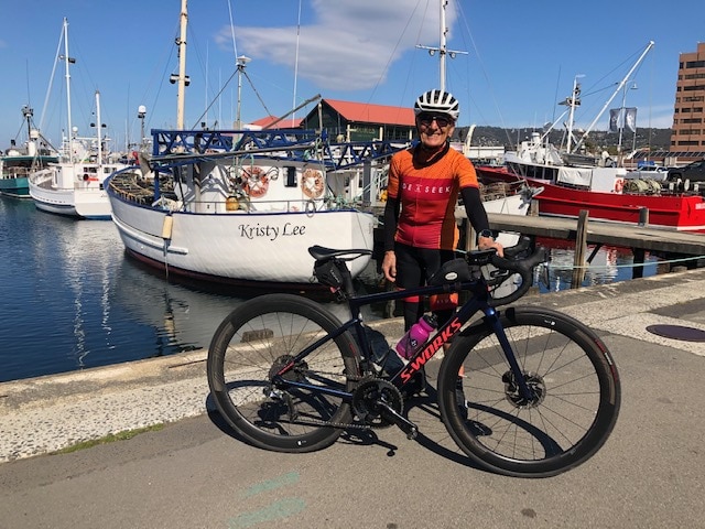 Cathy is posing behind her black road bike with the Constitution Docks in the background.