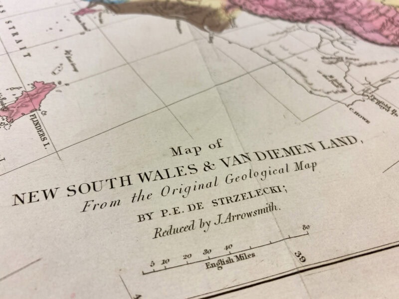 A close-up of a vintage map titled "Map of NEW SOUTH WALES & VAN DIEMEN LAND, From the Original Geological Map BY P.E. DE STRZELECKI; Reduced by J. Arrowsmith."