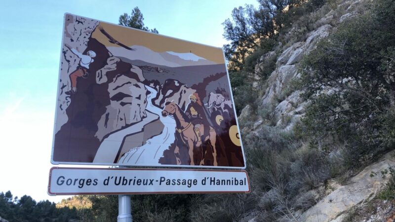 The Gorges d'Ubrieux sign. A steep, rocky hill behind.