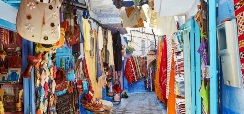 Gran Socco Madina. Isles of brightly coloured fabrics hang along the walls of the market.