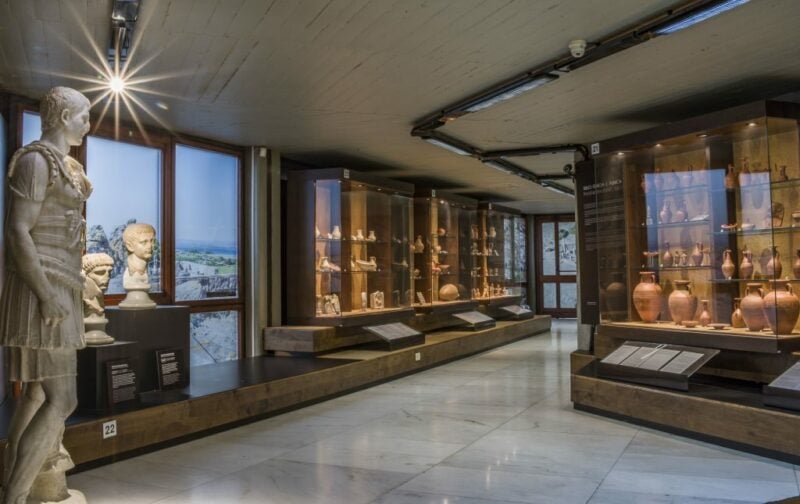 Inside a museum. There are display cases and floor to ceiling windows along the corridors.