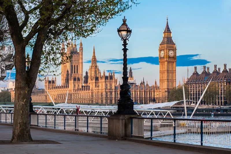Photo of Big Ben and Westminster Abbey across the river, taken from the South Bank of London, with an early morning sky behind.