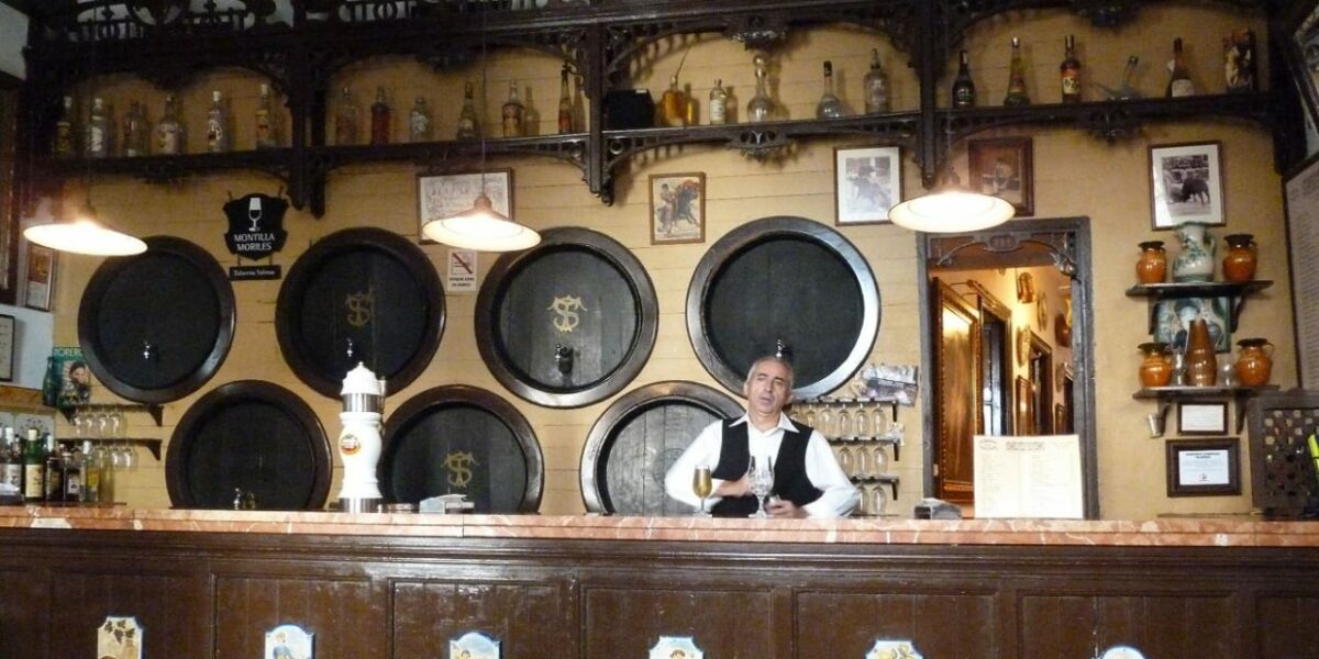A waiter stands behind a large bar.
