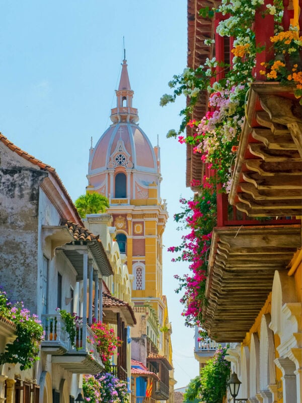The elegant bell tower of Cartagena’s cathedral rises above vibrant colonial streets adorned with balconies overflowing with flowers