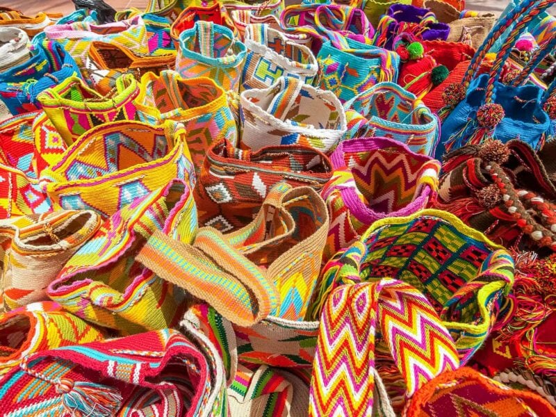 Colourful handwoven Wayuu mochila bags displayed in vivid patterns.