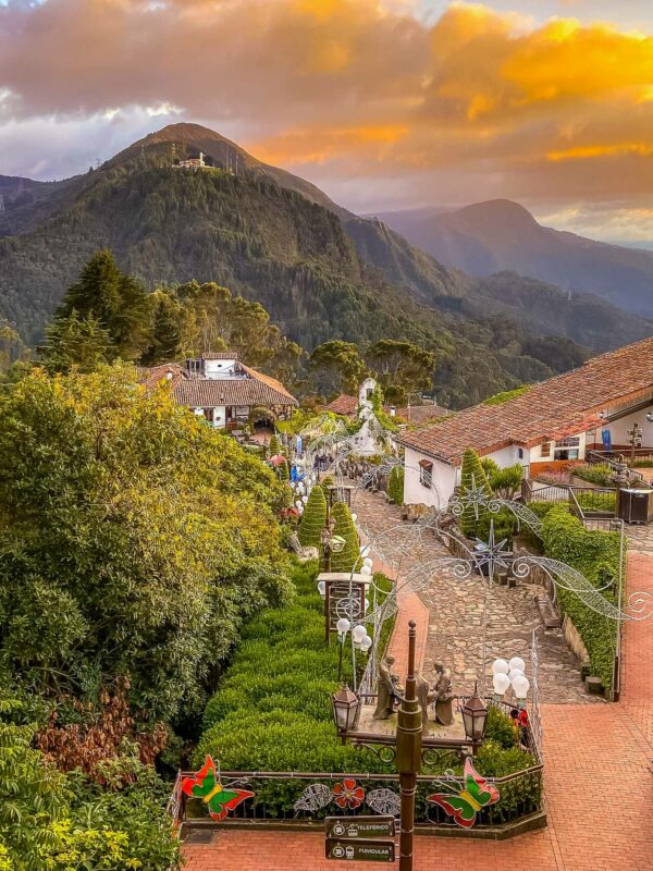 Sunset over Monserrate with cobblestone streets and Andean houses in the foreground.