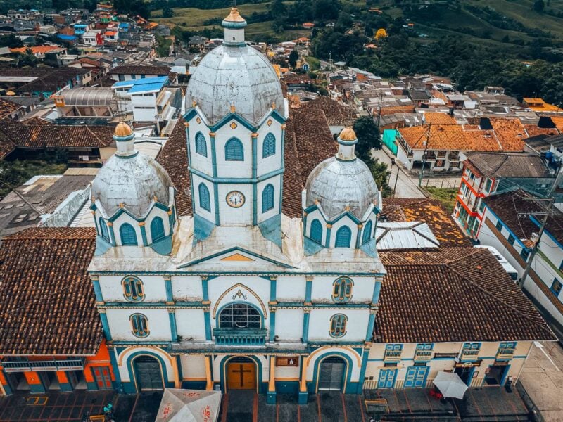 Aerial view of a white and blue-domed church surrounded by tiled rooftops in Filandia, Colombia.