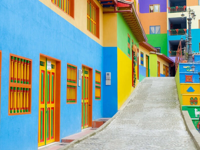Row of vividly painted houses in Guatapé with bold yellow, blue, green, and red facades.