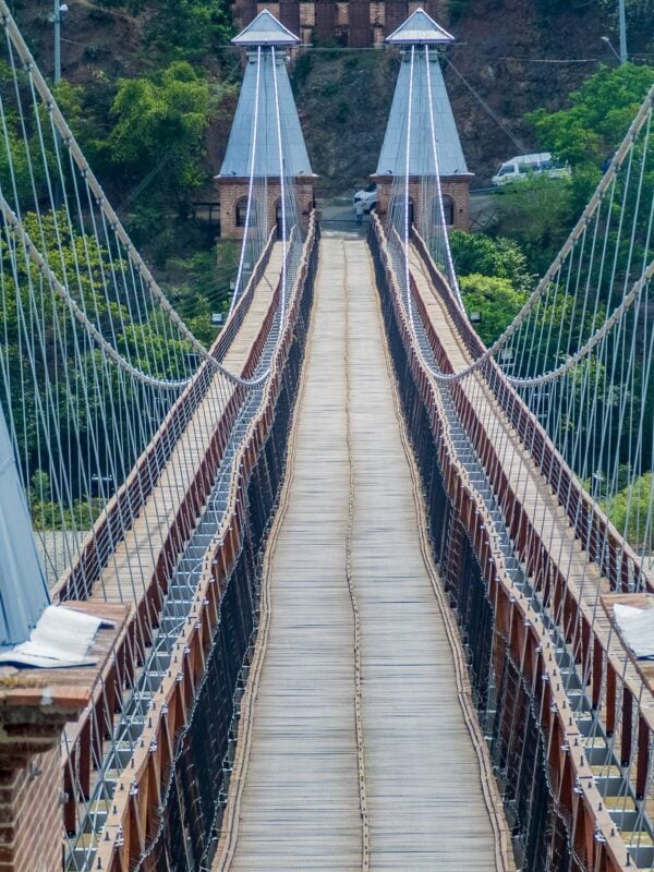 The historic suspension bridge of Santa Fe de Antioquia stretching across the valley, lined with cables and towers.
