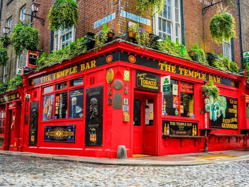 Temple Bar pub stands out with its bright red façade, hanging flower baskets, and cobbled street in Dublin’s cultural quarter.