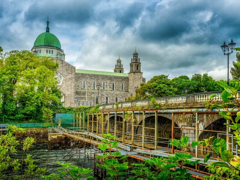 The white cast-iron Ha’penny Bridge arches over the River Liffey, with historic Galway Cathedral in the background