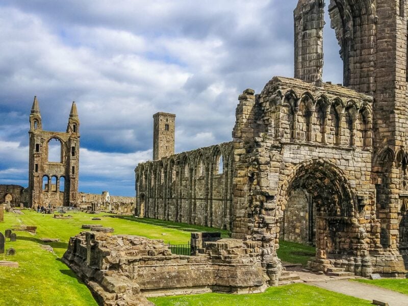 Stone ruins of St Andrews Cathedral against a bright blue sky.