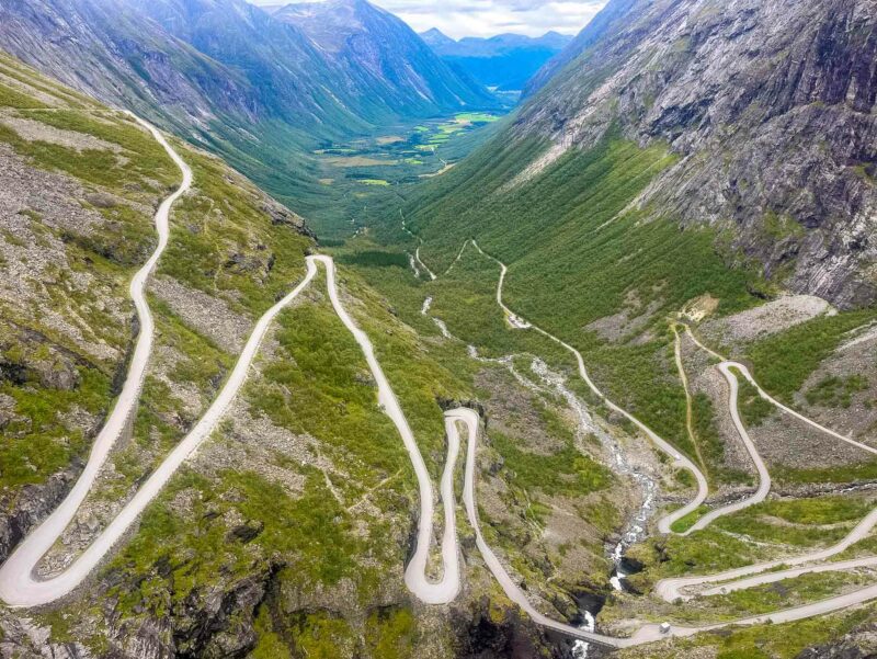 Aerial view of the famous Trollstigen road, with steep switchbacks winding through a dramatic green valley.