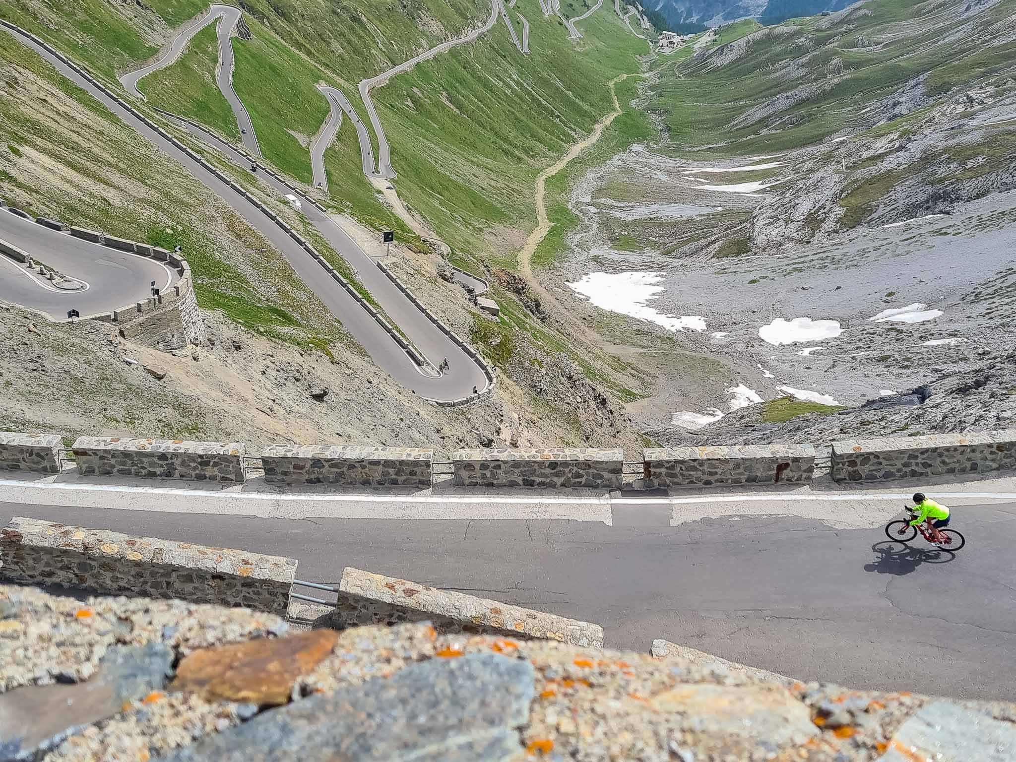 Cyclist on winding alpine mountain road with hairpins