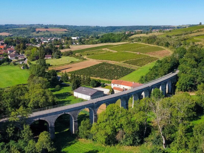 Stone railway viaduct over green rural farmland