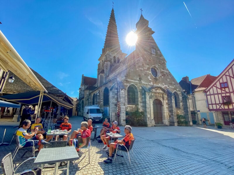 Cyclists relaxing at café beside historic village church