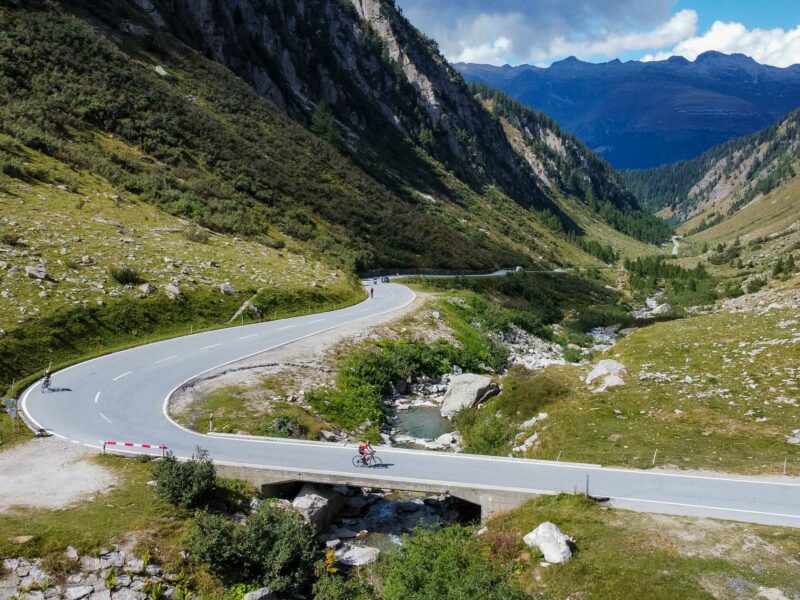 Cyclists on winding mountain road in alpine valley