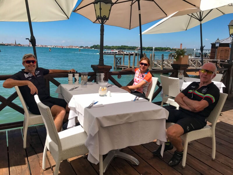 Three cyclists relaxing at waterfront café in Venice