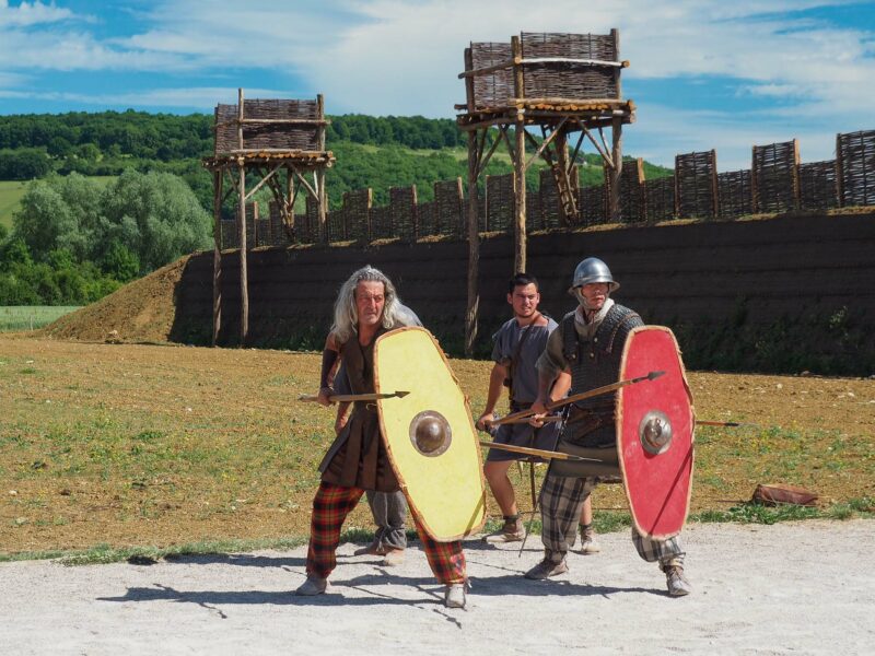 Historical re-enactors with shields in front of wooden fort watchtowers