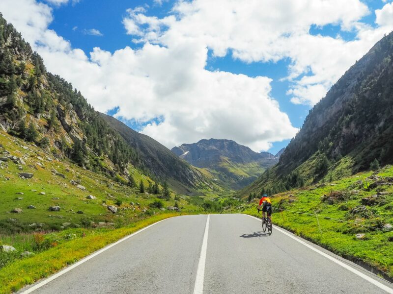 Cyclist riding through scenic mountain valley road