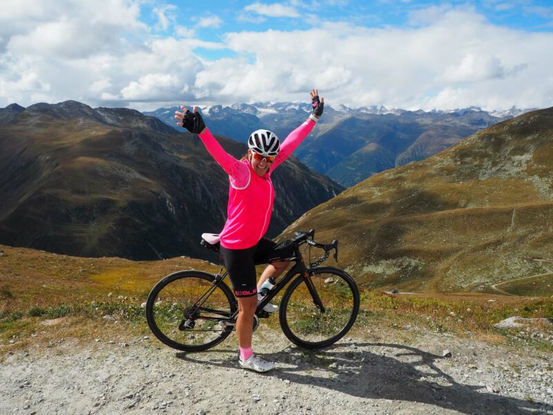 Cyclist celebrating on mountain road with alpine views