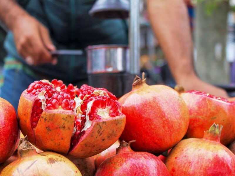 Fresh pomegranates at market stall, one cut open