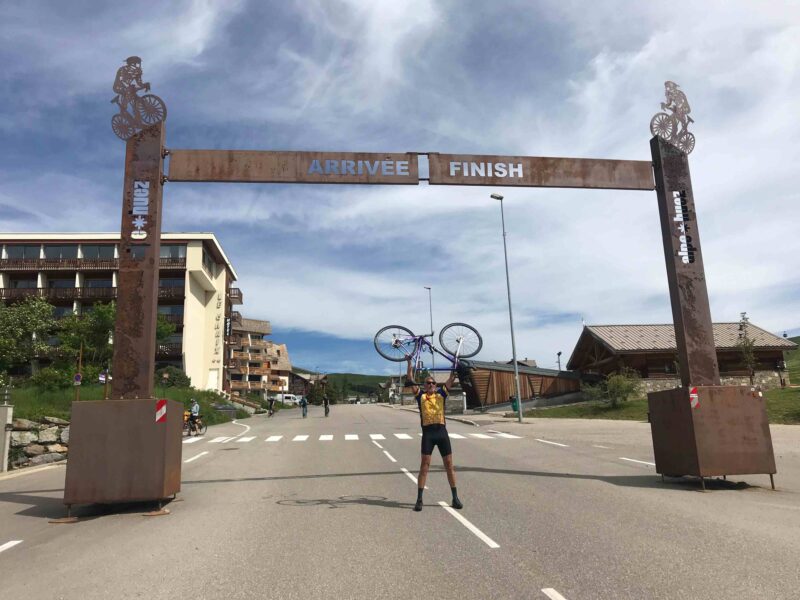 Paul holding his bike above his head at the Alpe d'Huez finish line