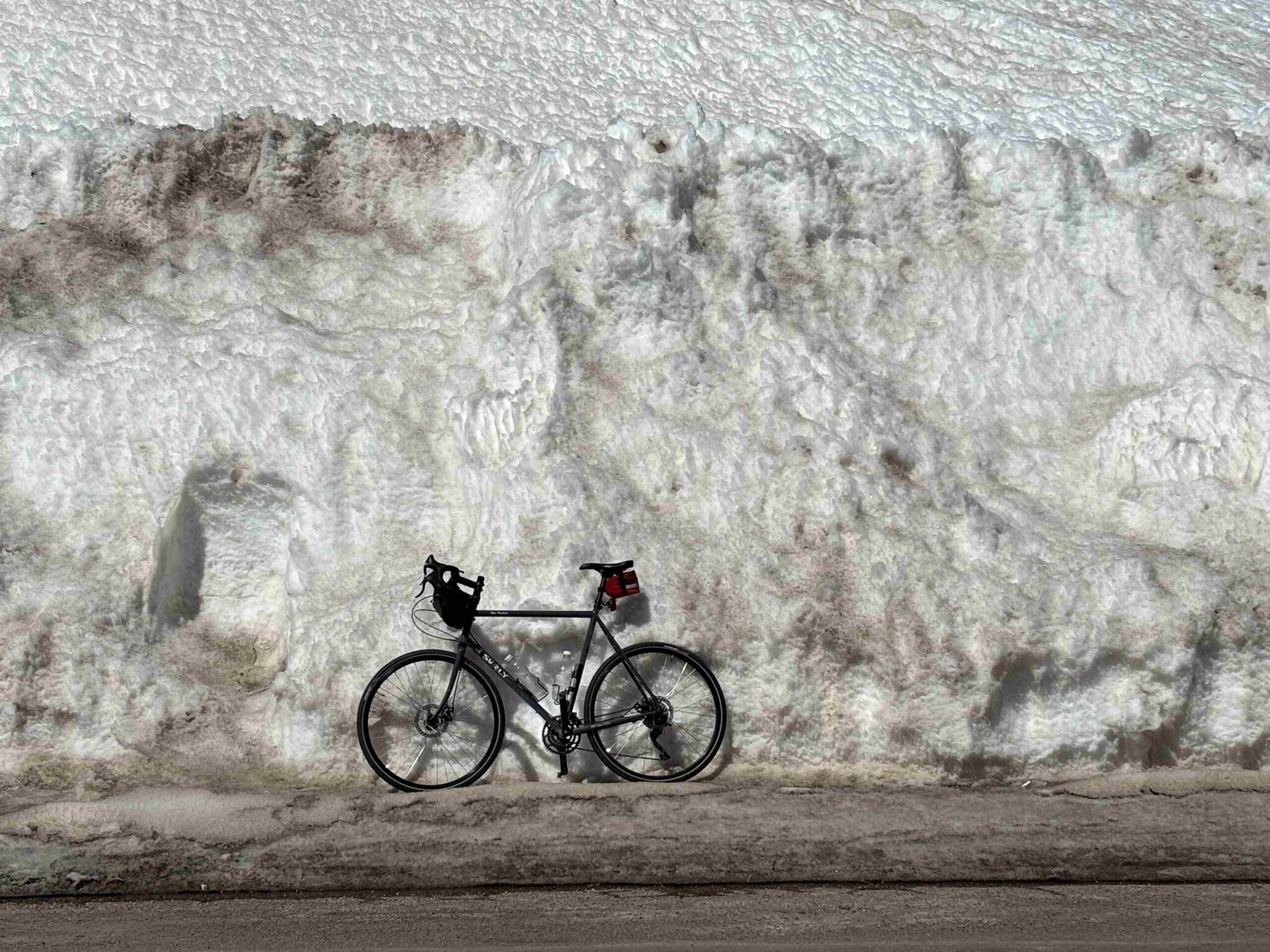 Paul's Surly bike leaning against a massive wall of snow on a Ride & Seek cycling adventure tours.