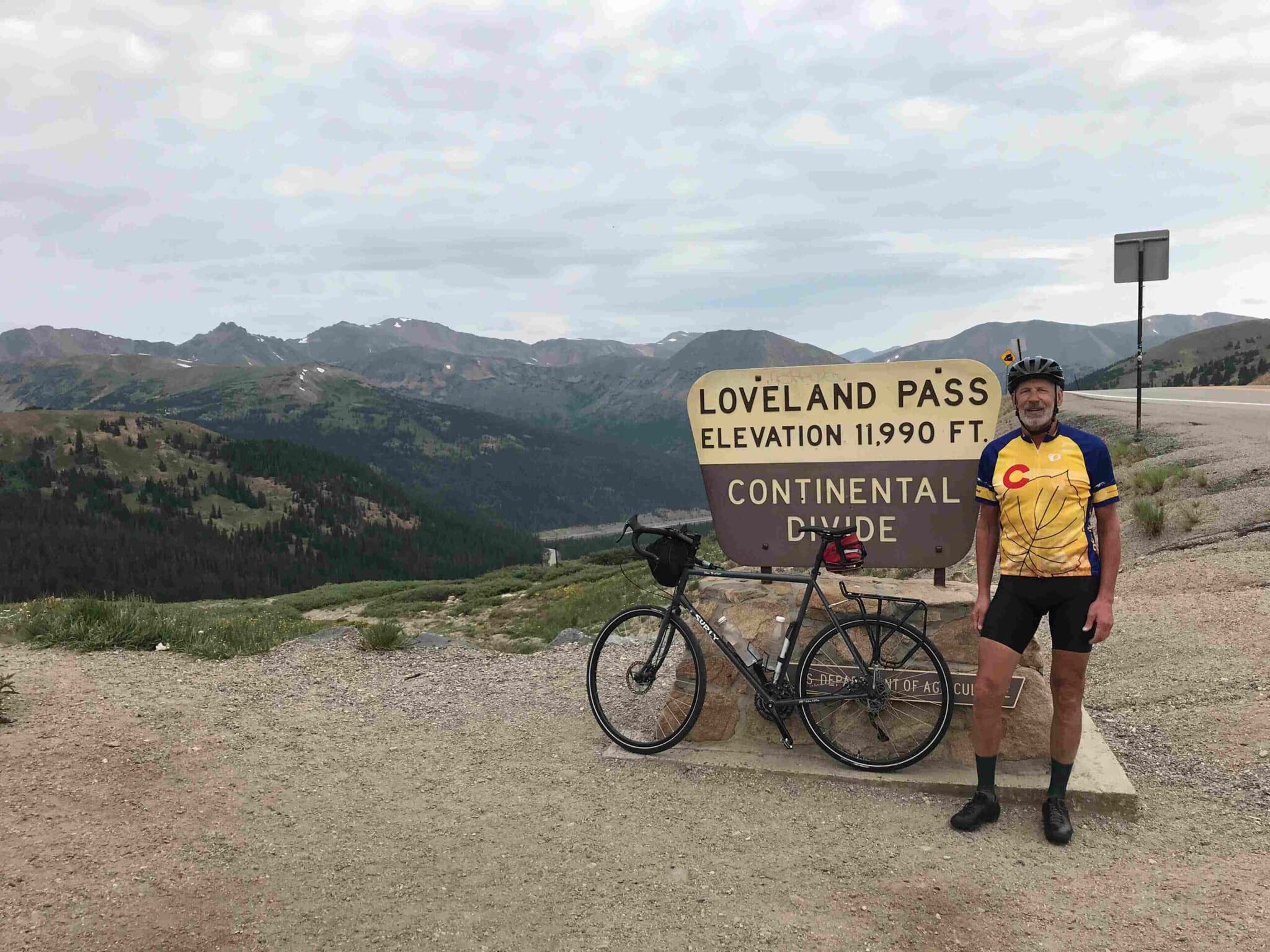 Paul standing next to his bike at the Loveland Pass Continental Divide elevation sign in Colorado