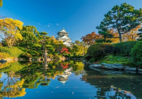 Samurai Cycling Tour Osaka Castle Garden A still lake surrounded by lush gardens. A white, traditional temple sits amongst the gardens in the background.
